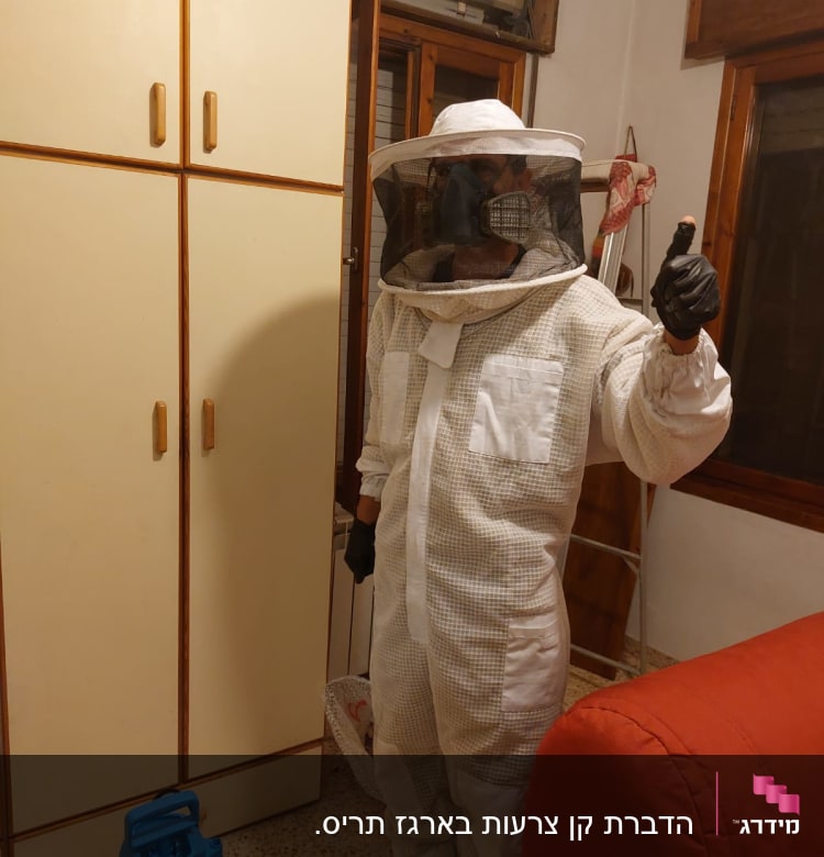 אדם בחליפת מגן עם מסכת רשת ומרסס צהוב